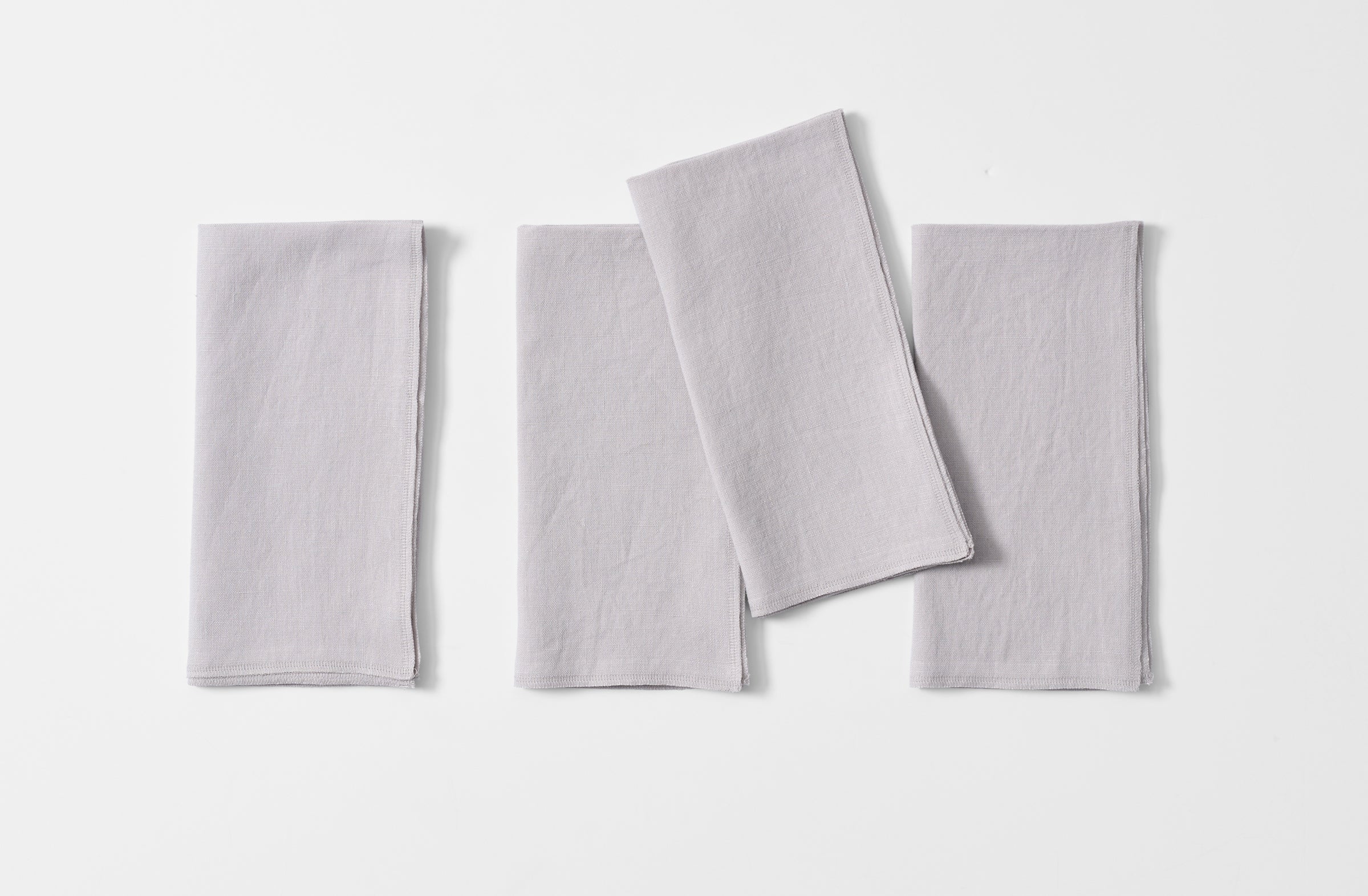 Four folded boxwood silver linen overlock napkins.