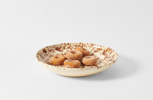 Seventeen inch brown on cream splatterware serving platter holding sugared doughnuts.
