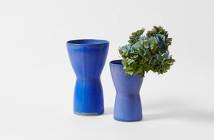 Christiane Perrochon bright blue large hourglass vase with bright blue medium hourglass vase holding hydrangeas.