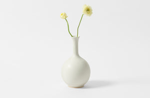 Christiane Perrochon cloud grey medium round bottle vase holding pale yellow ranunculus.