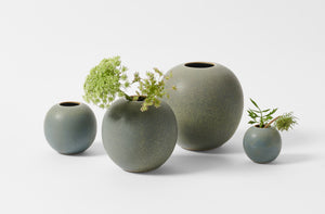 Group of four Christiane Perrochon grey blue round vases with arrangement of queen annes lace.