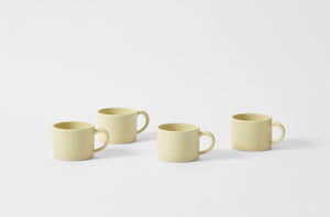 Four Christiane Perrochon pale yellow mugs.