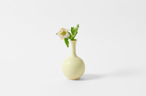 Christiane Perrochon pale yellow small bottle vase holding pale pink hellebore flowers.