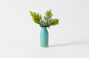 Christiane Perrochon medium turquoise bottle vase with yellow flowers.