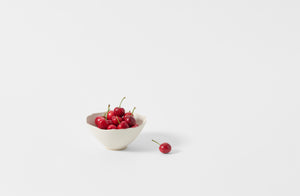 Christiane Perrochon white petite scallop bowl holding red cherries.