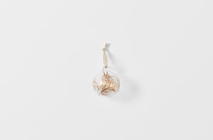 Clear glass ball ornament with gold branches strung with linen tape