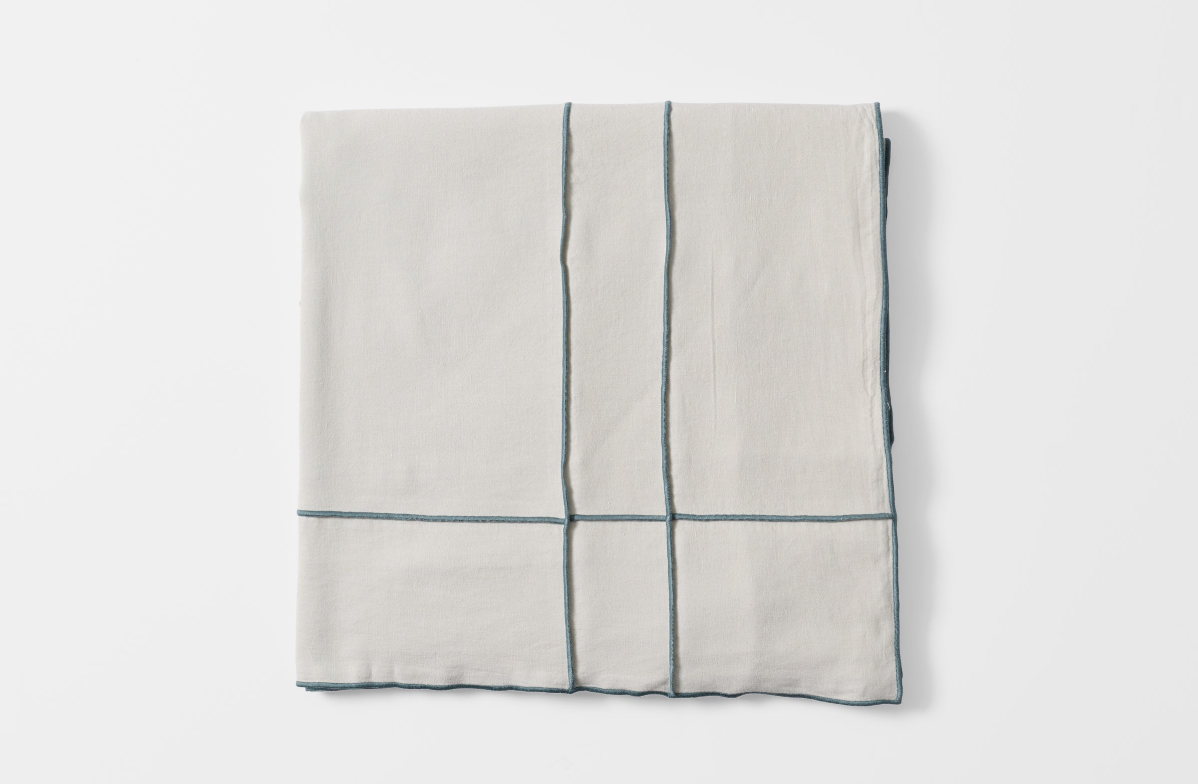 Folded embroidered grid tisana tablecloth.