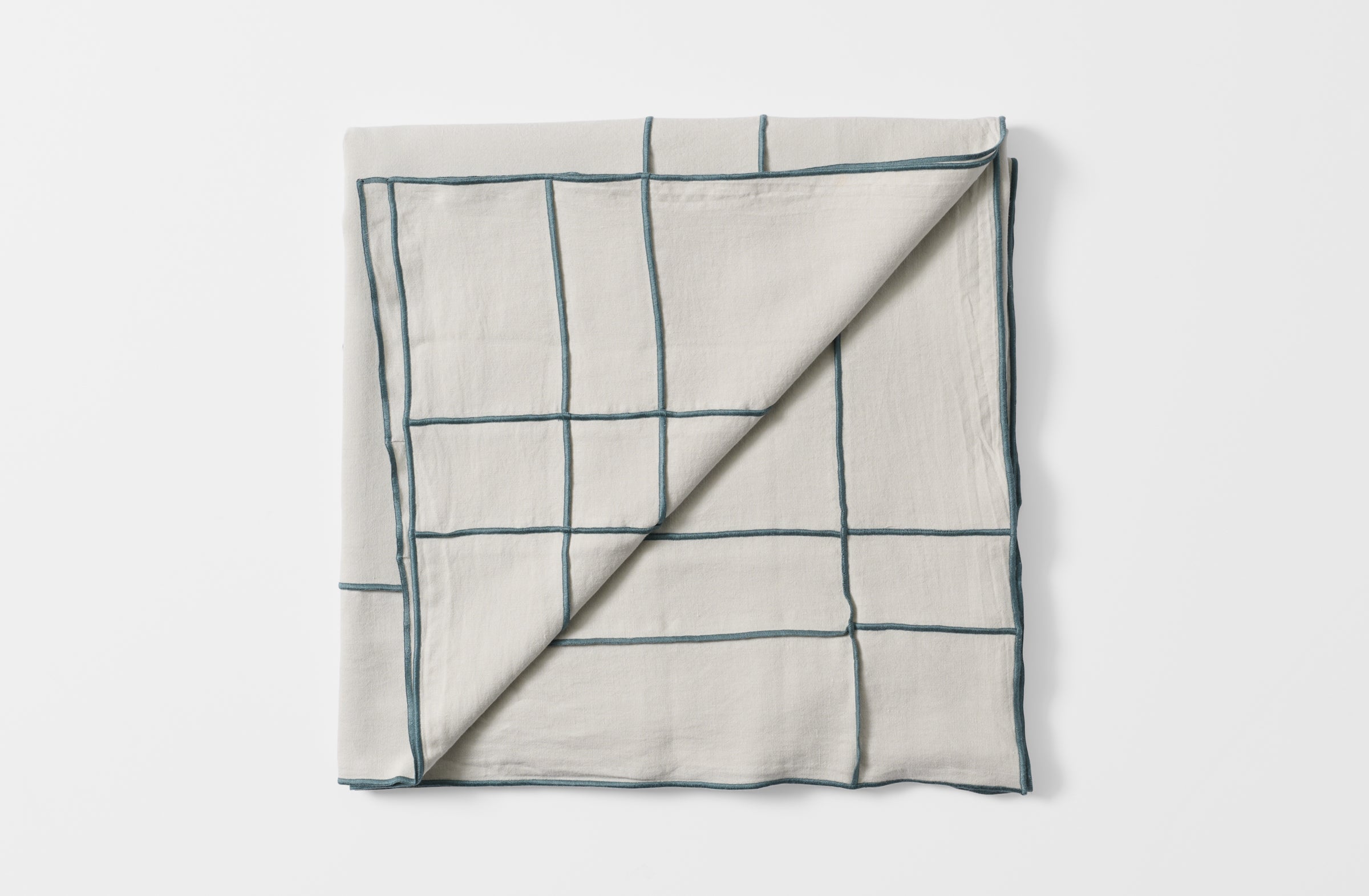 Folded embroidered grid tisana tablecloth with detail of reverse.