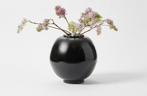 Faye Toogood black moon vase with branches of lilac.