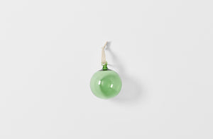 Single green glass ornament strung with linen tape