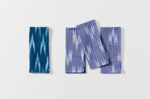 Group of four Gregory Parkinson azul triangle napkins with one showing reverse pattern