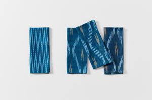 Group of four folded Gregory Parkinson faded blue triangle napkins with one showing the reverse pattern