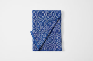 Hand printed checkered floral indigo linen tablecloth folded with detail of reverse.