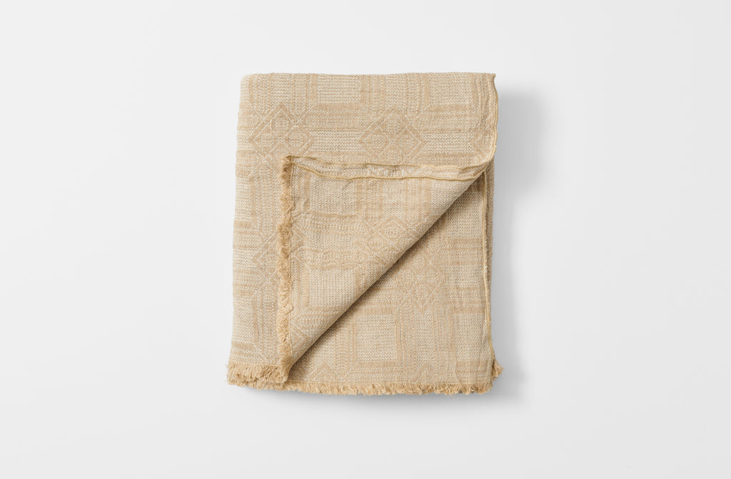 Homespun natural tablecloth folded with detail of reverse.