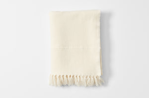 Ivory fringed cashmere throw blanket folded.