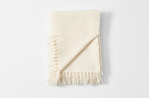 Ivory fringed cashmere throw blanket folded with detail of reverse