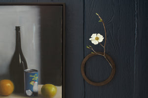 Keiichi Tanaka circular ceramic wall vase with floral hanging next to a still life painting by Karyn Lyons.