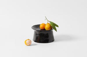 La Mere small ebony pedestal plate holding mandarin oranges.