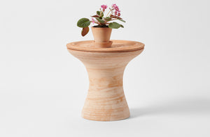 Large terracotta pedestal pot as table with potted plant on top.