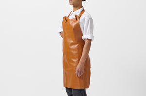 Model wearing Malle W. Trousseau tan leather apron.