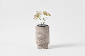 Michael Verheyden grigio carnico marble vase with leather lid holding stems of Queen Anne's Lace.