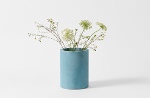 Turquoise Michael Verheyden wide concrete vase with Queen Anne's Lace and wax flowers.