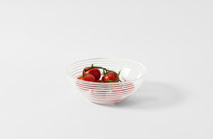 White stripe murano glass salad bowl holding red summer tomatoes. 