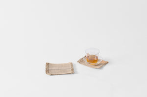 Set of six natural and black stripe woven coasters with Lobmeyr tea glass.