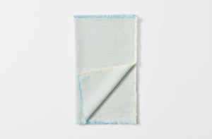 Pale blue fringed runner folded with detail of reverse.