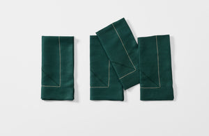 Four folded bottle green linen Peter Speliopoulos hemstitch napkins.