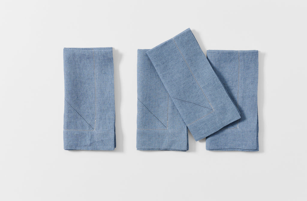Four folded Peter Speliopoulos light wash denim napkins