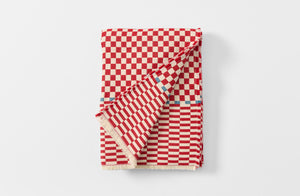 Red and cream checkered cashmere throw folded with detail of reverse.