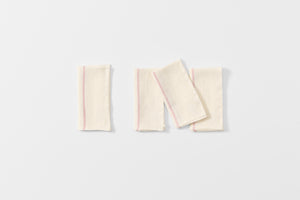 Four folded embroidered red stripe white linen napkins.