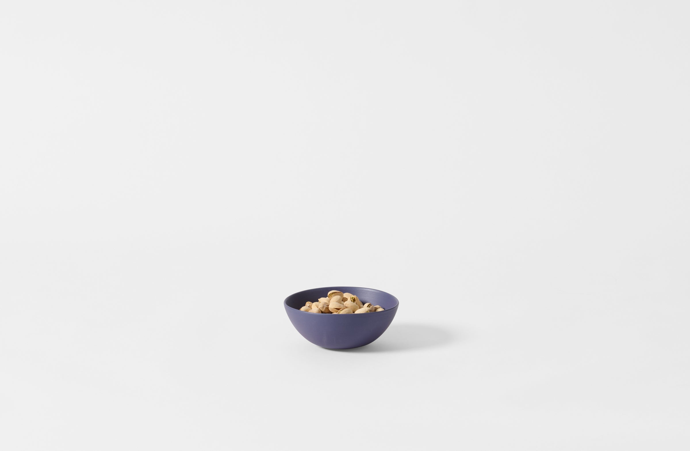 Extra small Rina Menardi blue shallow bowl with pistachios.