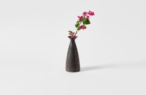 Takashi Endo black sake bottle holding stem of pink berries.