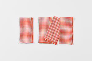 Four tangerine gingham napkins folded.