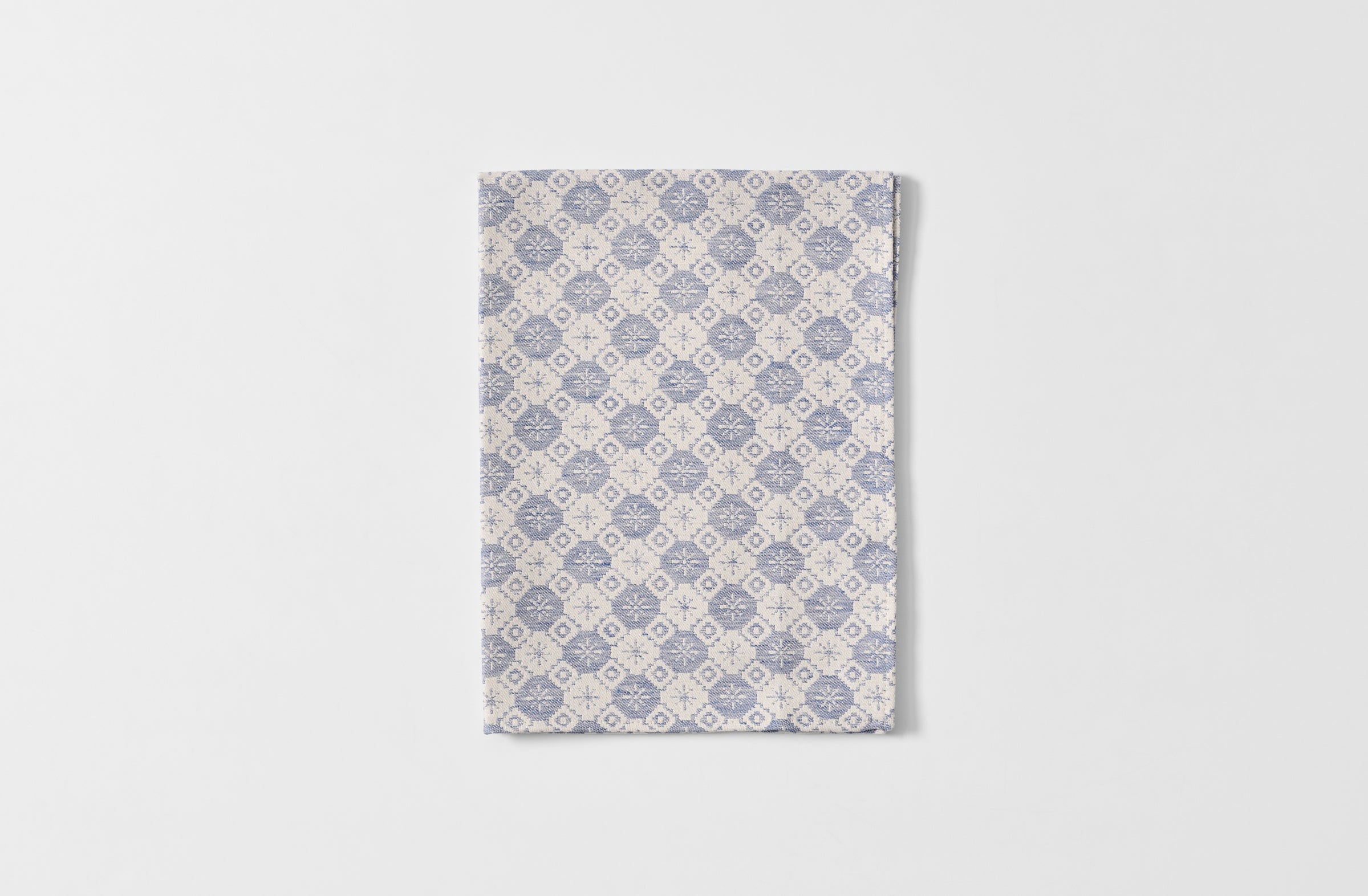 Folded Tori Murphy indigo tapestry kitchen towel.