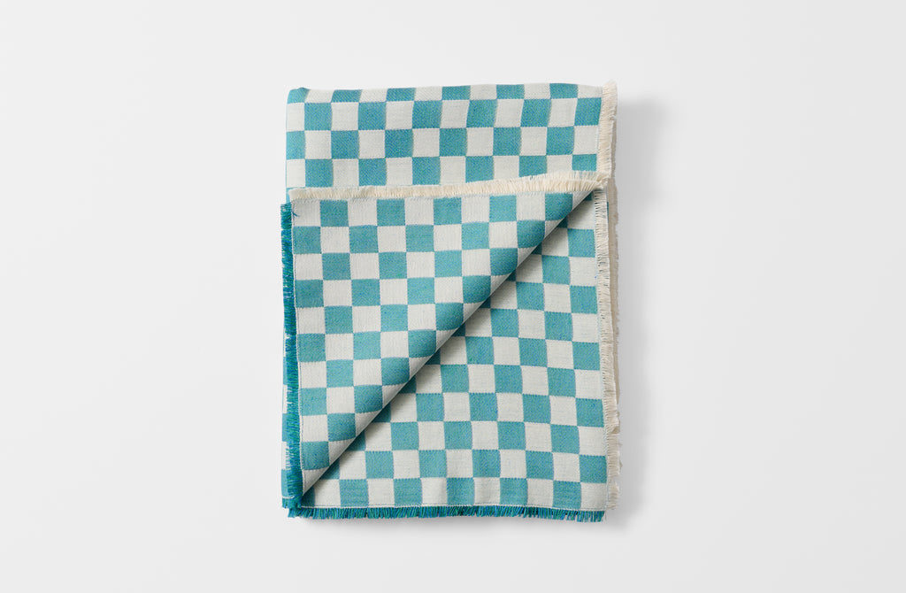 Folded turquoise check tablecloth with detail of reverse.