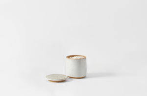 White ceramic container with lid on a light gray background