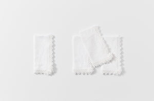 Four white macrame edge linen napkins