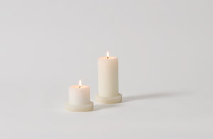 White onyx pillar candle holders with lit pillar candles.