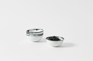 Four Yuta Miyazaki petite indigo rim bowls with one holding blackberries.