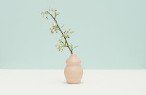 Dana-bechert-small-peach-curvy-vase-with-floral-against-pale-turquoise-background