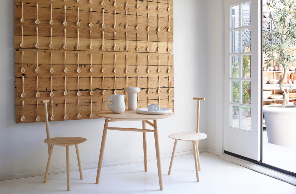 At-MARCH-sawkille-ash-pedestal-table-with-faye-toogood-ash-spade-chairs-set-with-cream-tabletop-in-front-of-joshua-vogel-spoon-installation-with-view-of-garden-through-doors