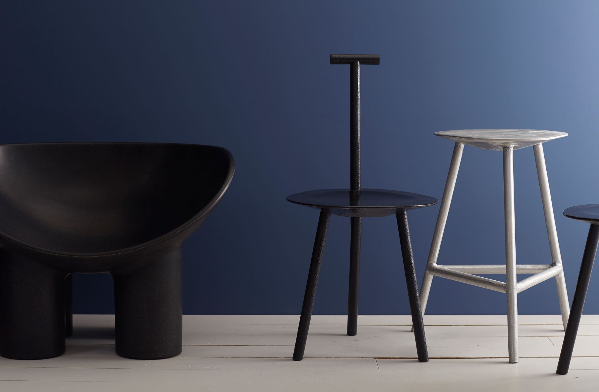 At-MARCH-faye-toogood-furniture-against-navy-background-including-aluminum-stool-and-rubber-spade-chair