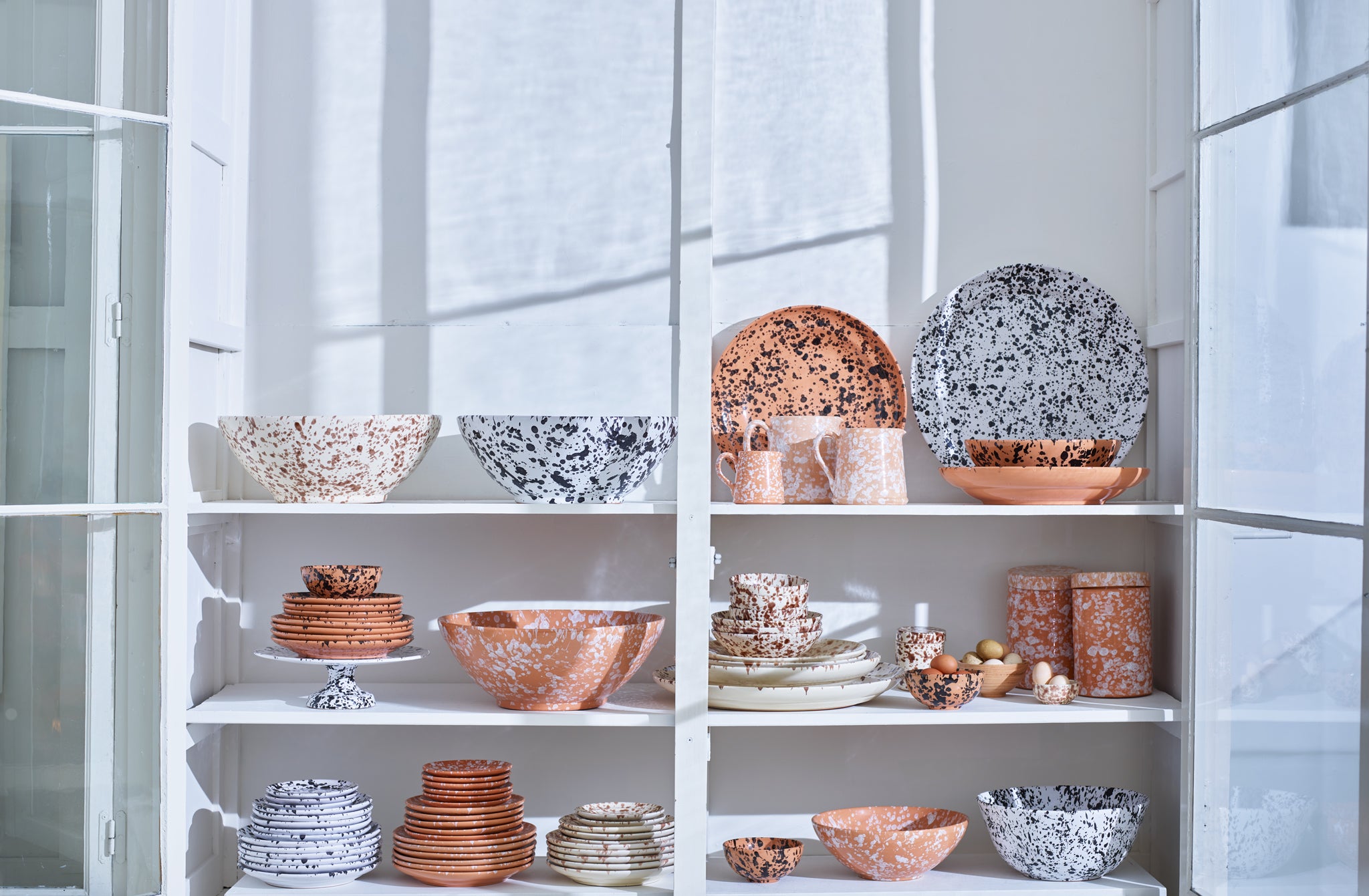 Mixed-Splatterware-Earth-Tones-stacked-in-a-light-filled-glass-cabinent-march-Default