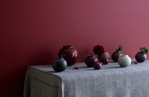 Christiane-Perrochon-Shiny-Raisin-boule-vase-with-mixed-petite-boule-vases-with-floral-on-patterned-tablecloth