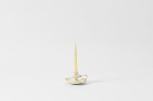 cream on white chamberstick candleholder with taper candle