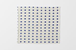 one unfolded gregory parkinson indigo square napkin showing the full repeat of the pattern