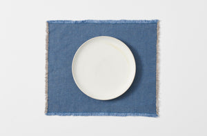 indigo blue hopsack linen fringed placemat shown from above with a white dinner plate